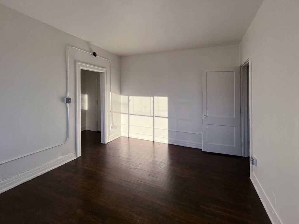 a bedroom with hardwood floors and white walls