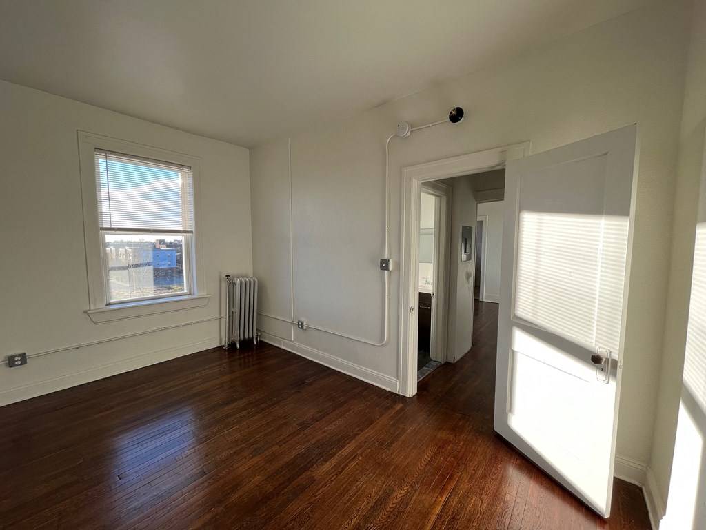 an empty room with hardwood floors and a radiator on the wall