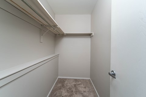 a walk in closet with white walls and a white door