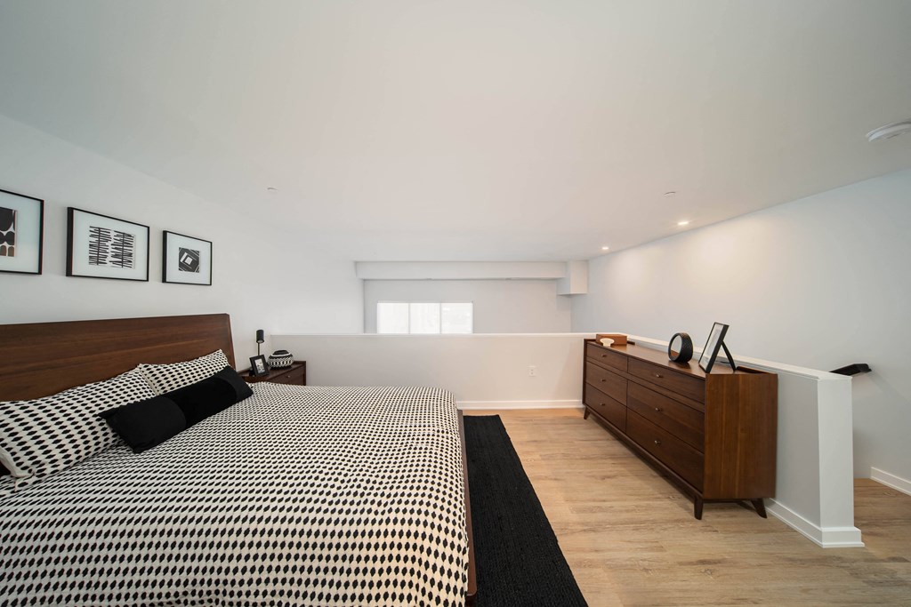 A bedroom with a bed, nightstand, and a dresser at The George, Ann Arbor, MI