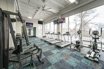 a gym with treadmills and other exercise equipment and a large window