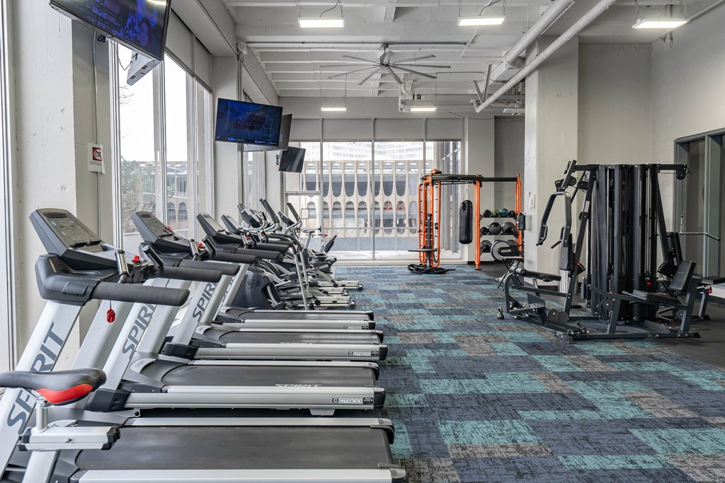 a gym with cardio equipment and a large window