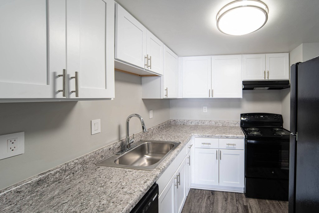 a kitchen with white cabinets and granite counter tops and a sink