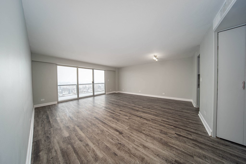 an empty living room with wood flooring and a window