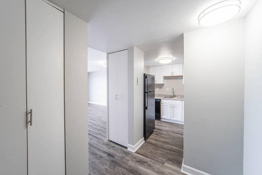 a renovated living room and kitchen with white cabinets and a black refrigerator