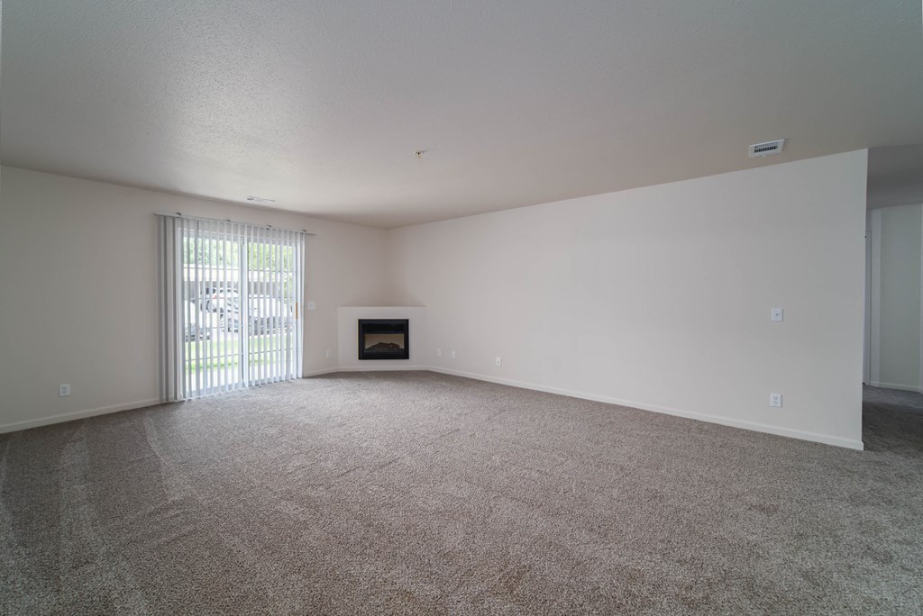 an empty living room with a fireplace and a sliding glass door