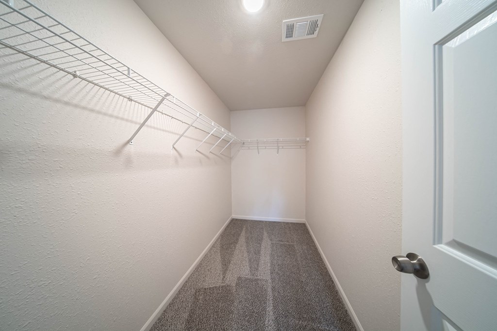 an empty room with a mirrored closet and a door to a room with white walls