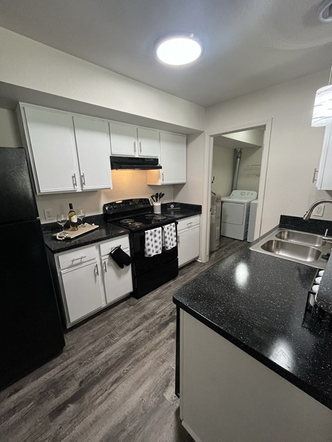 a kitchen with white cabinets and black counter tops and a sink