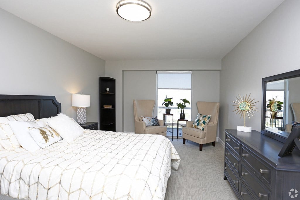 a bedroom with a large bed and a living room with chairs