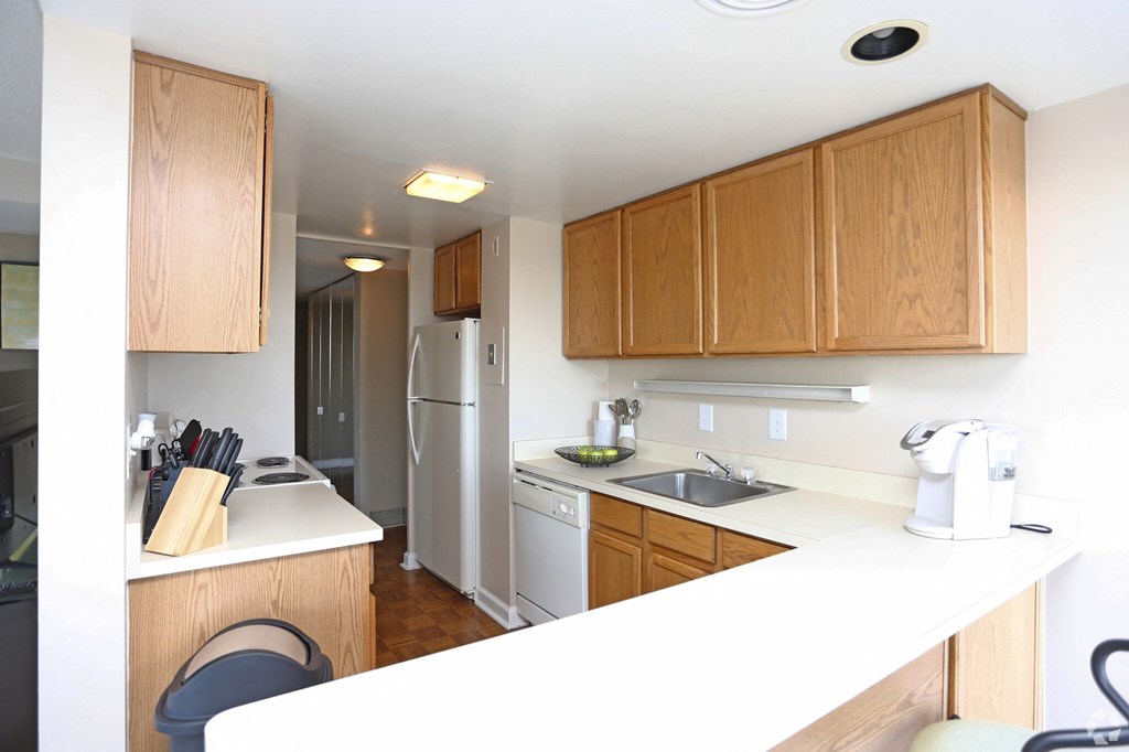 a small kitchen with white counter tops and wooden cabinets