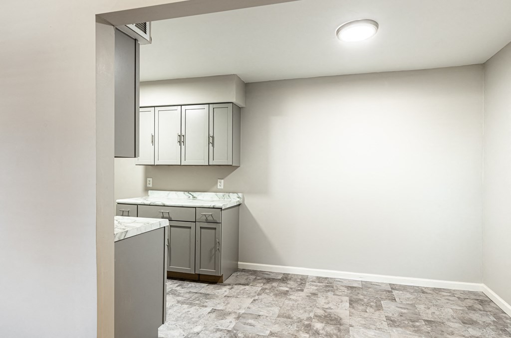 an empty kitchen with white walls and white counter tops and gray cabinets
