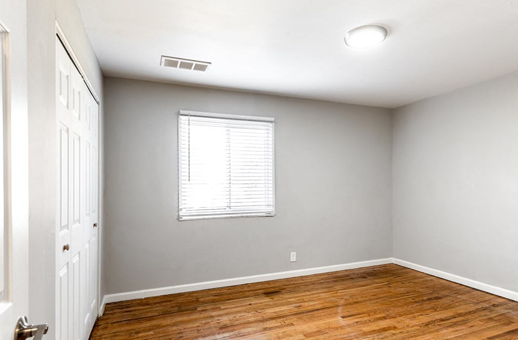 an empty room with wood floors and a window