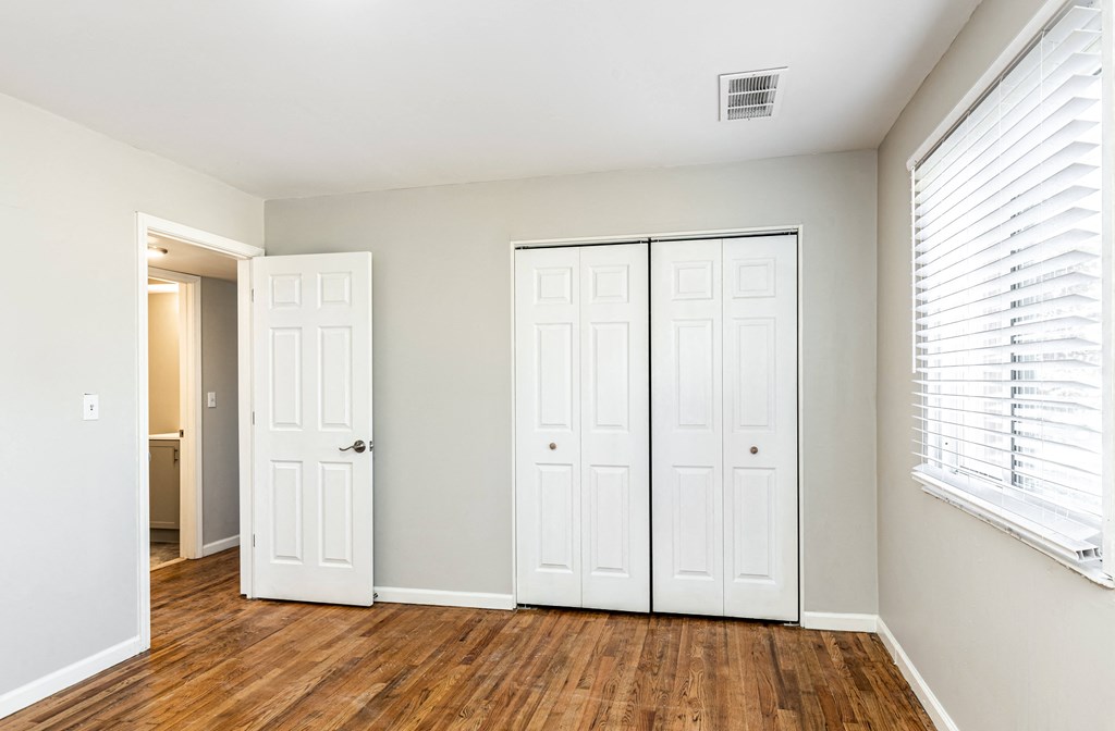 an empty living room with white doors and wood floors