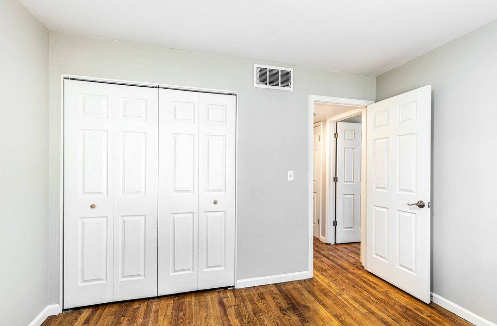 an empty room with white doors and a door to a closet