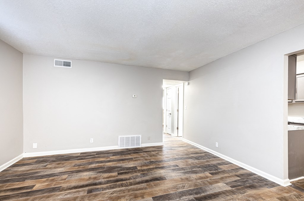 an empty living room with white walls and wood flooring