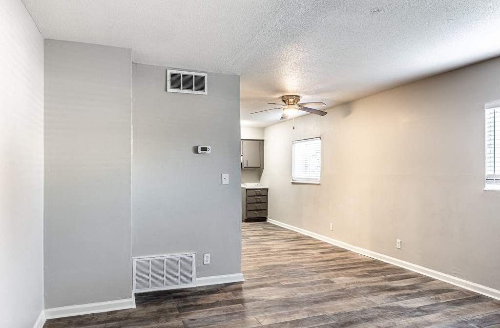 an empty living room with a ceiling fan