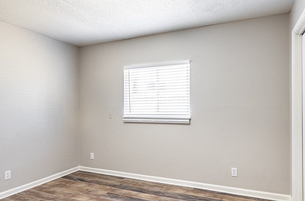 an empty room with a window and a wooden floor