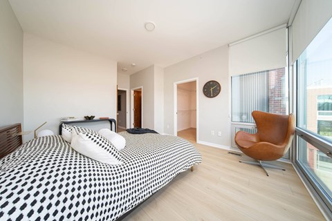 A bedroom with a large bed and a chair.