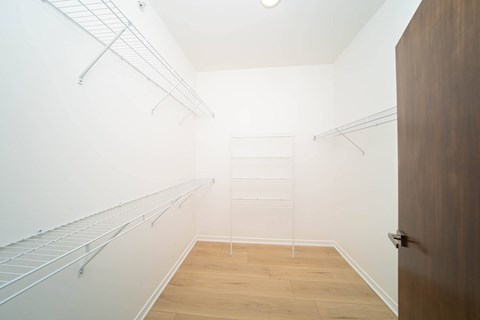 A walk in closet with a wooden floor and white walls.