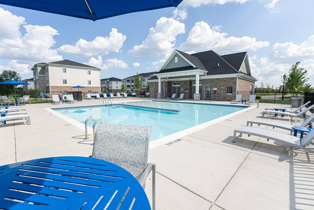 Bright blue sparkling pool with seating surrounding.