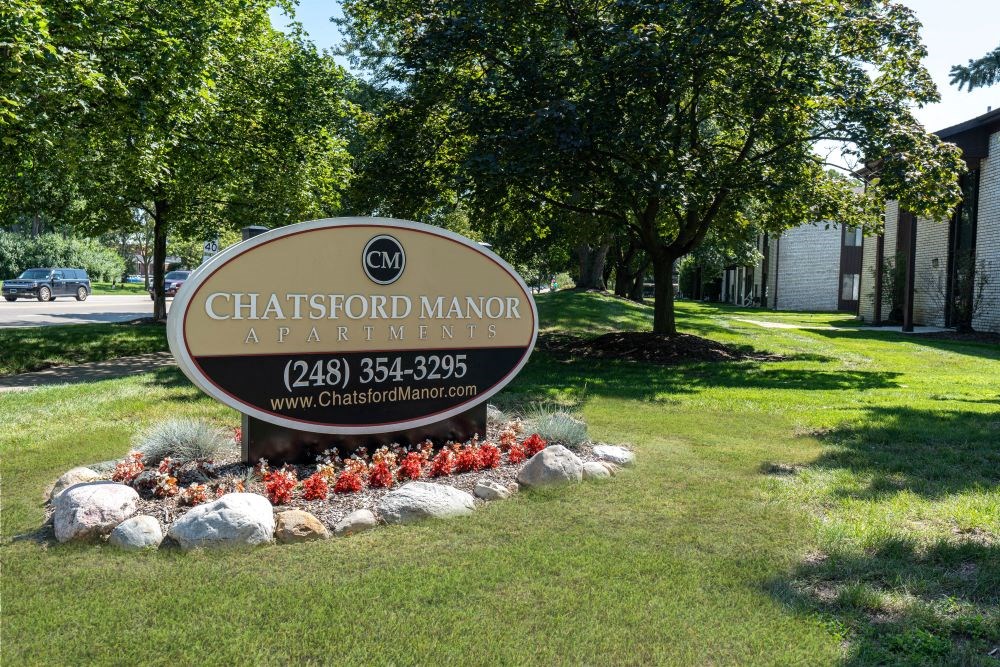 a sign in the grass in front of a park