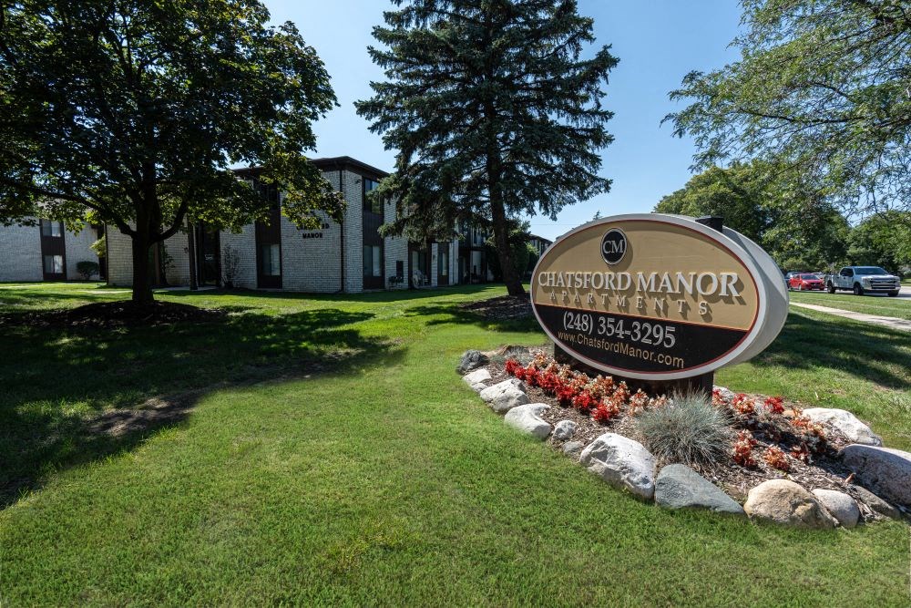 a sign in front of a grassy area with trees in the background