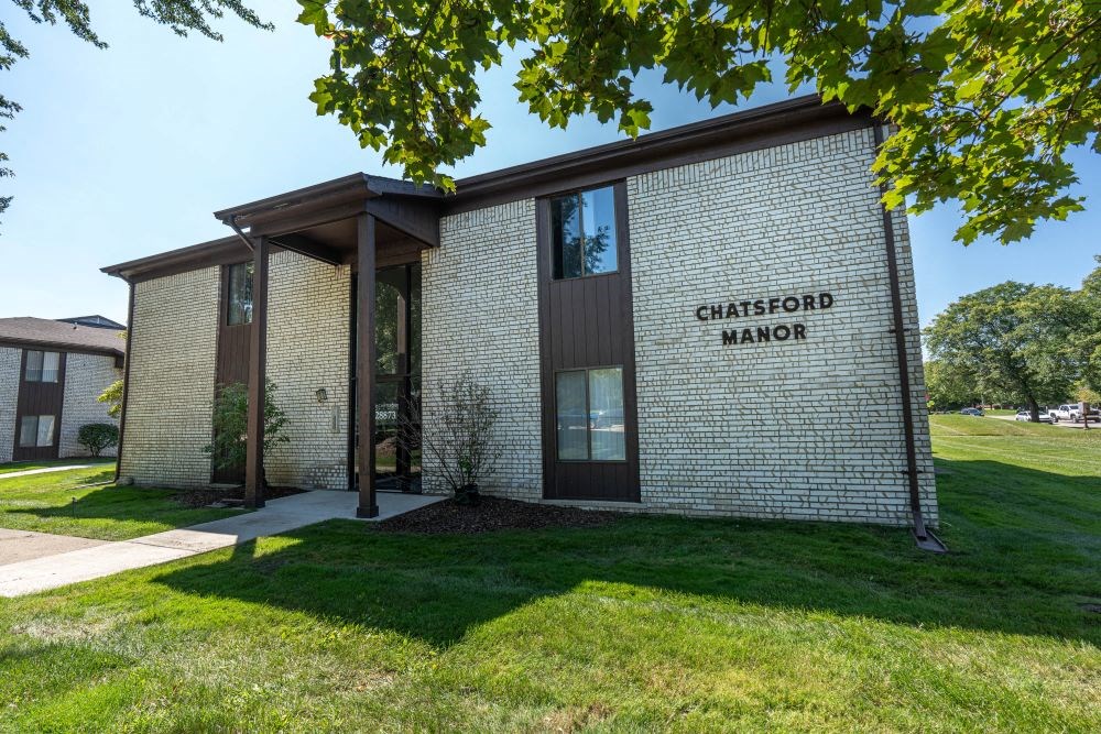 the front of a church office building with grass and a tree