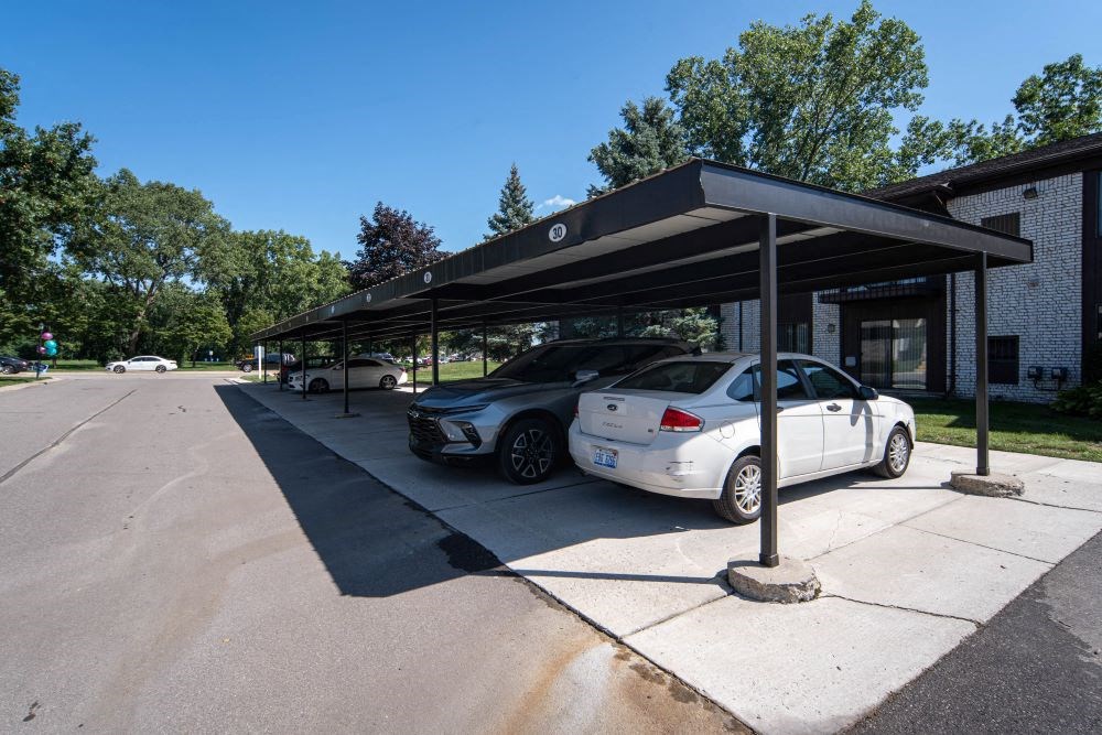 a parking lot with two cars under a car shade