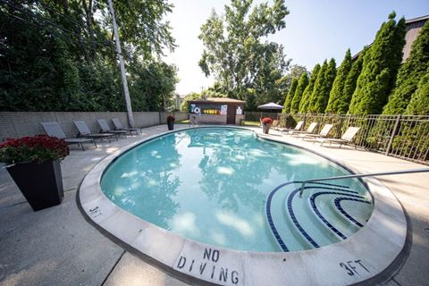 a round swimming pool with lounge chairs and trees in the background