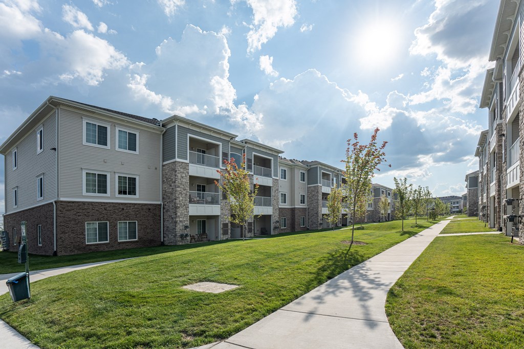 Exterior view of community, paved sidewalk through green grass.