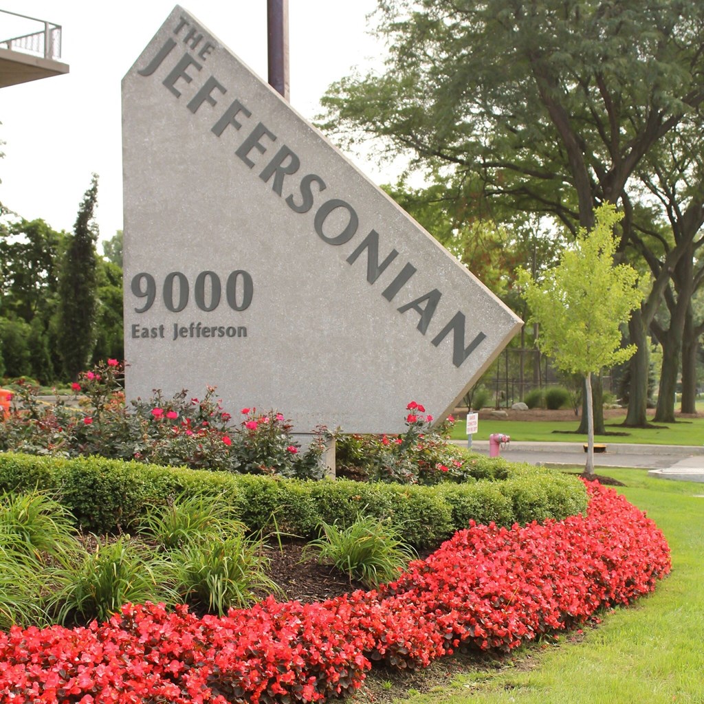 a sign for the jeffersonian in front of red flowers