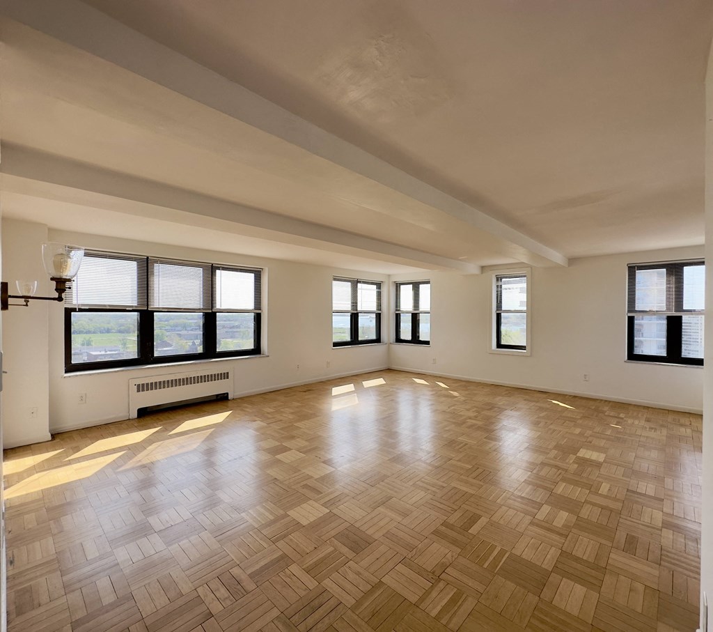the living room of an empty apartment with wood flooring and windows