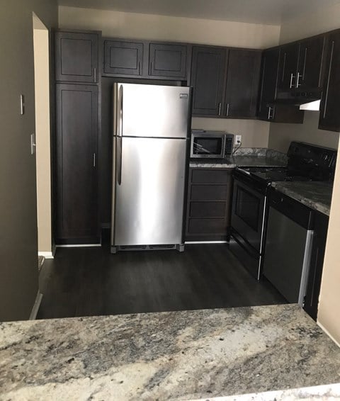a kitchen with black cabinets and a stainless steel refrigerator