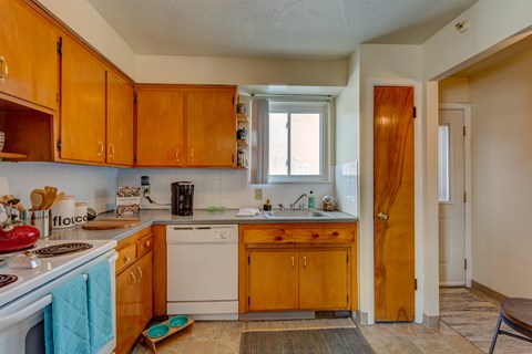 A kitchen with wooden cabinets and a white stove top oven.