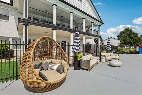 A wicker chair with cushions is in the foreground of a patio area.