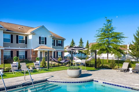 a swimming pool with chairs and umbrellas in front of a house