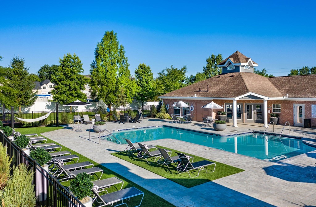 a swimming pool with lounge chairs in front of a building with a resort style pool
