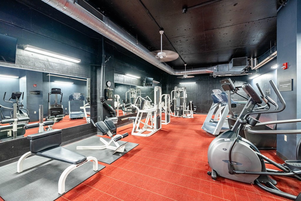 a gym with various exercise equipment on the floor and a ceiling light