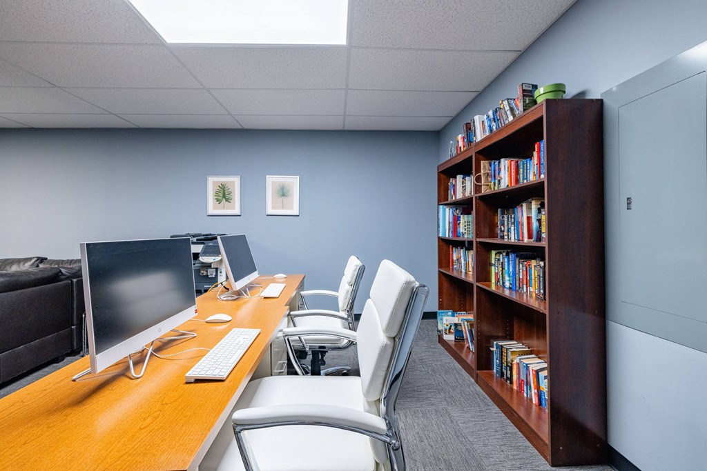 an office with a desk with a computer and a book shelf