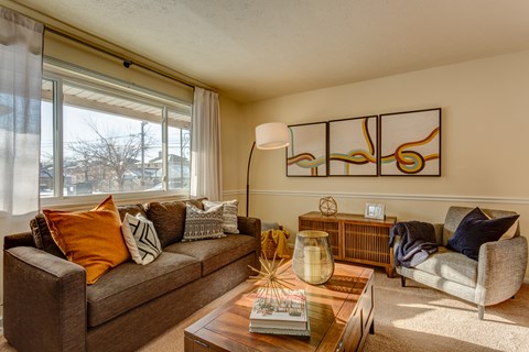 A living room with a brown couch, a coffee table, and a large abstract painting on the wall.