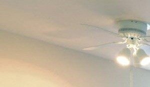 Living room with grey carpet, white walls, a large picture window and ceiling fan.