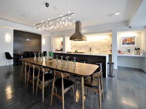 a long table with chairs in a room with a kitchen at The George, Ann Arbor, MI