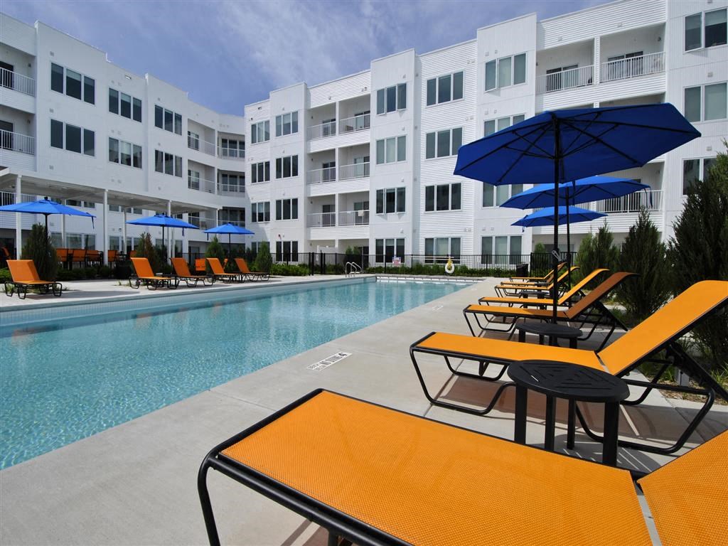 a pool with a bunch of lounge chairs and umbrellas a pool with a bunch of lounge chairs and umbrellas at The George, Ann Arbor, 48104