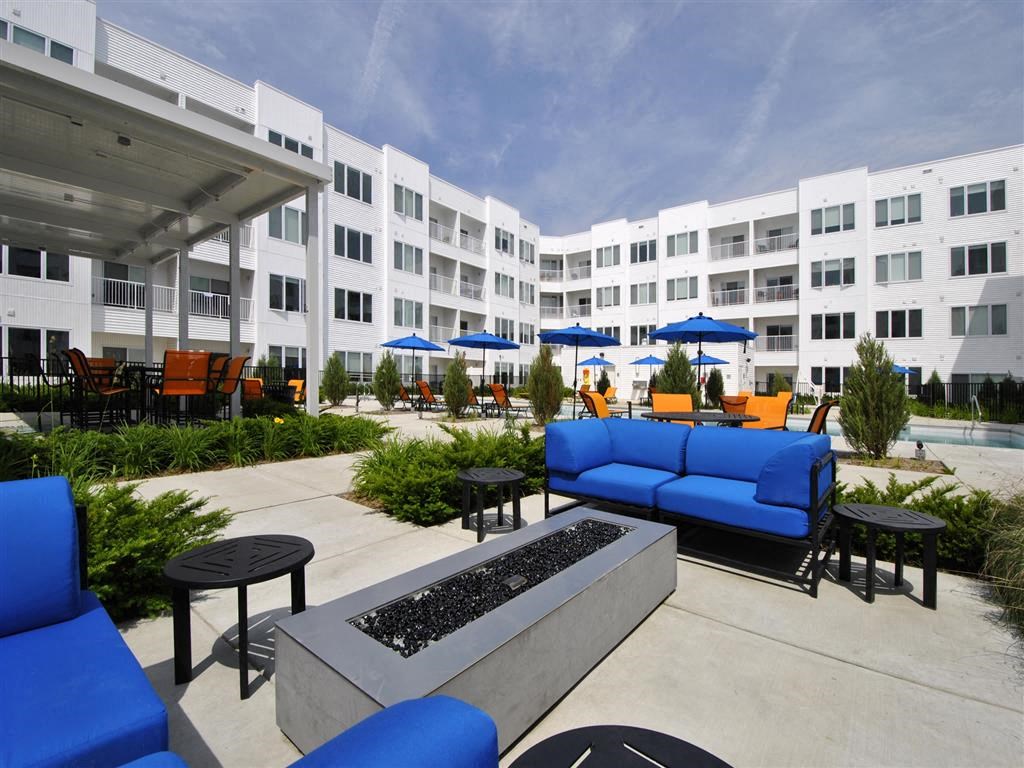 a patio with blue couches and chairs and umbrellas in front of an apartment building a patio with blue couches and chairs and umbrellas in front of an apartment building at The George, Michigan, 48104