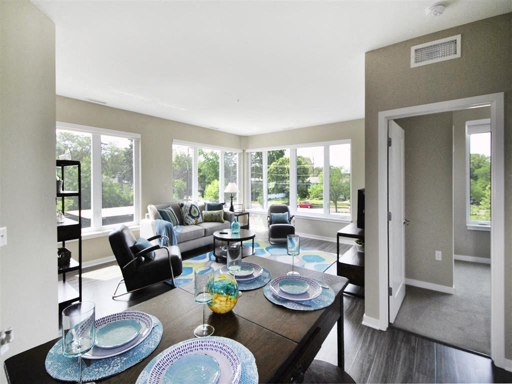 a living room with a table and chairs in front of a window at The George, Ann Arbor, 48104