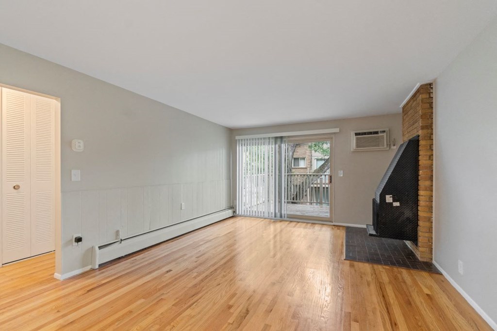 a living room with a hardwood floor and a sliding glass door to a balcony
