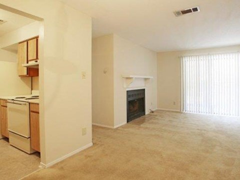 an empty living room and kitchen with a fireplace