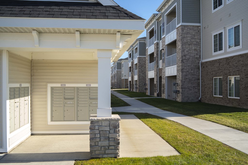 Photo of mailbox station with pillar in front and building behind.