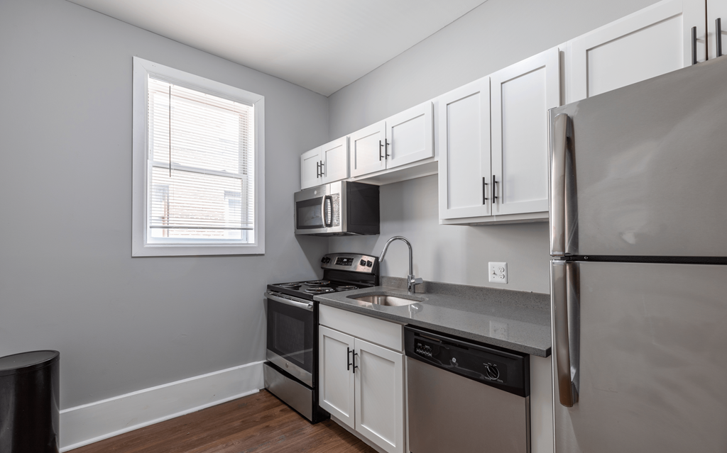 an empty kitchen with stainless steel appliances and white cabinets