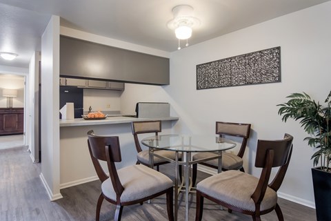 a dining area with a glass table and chairs and a kitchen